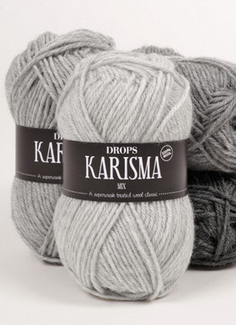 Puede incluir: Tres ovillos de lana gris con una etiqueta que dice "DROPS KARISMA MIX. Un cl&aacute;sico de lana tratada superwash."