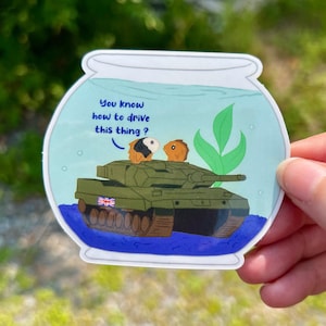 May include: A sticker depicting a fishbowl scene with a green tank and two guinea pigs. The text reads "You know how to drive this thing?" above the tank. The tank features a British flag, adding a humorous touch.