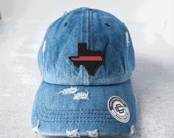 May include: Distressed denim baseball cap with a black and red Texas state outline patch. The hat features a curved brim, adjustable strap, and a circular patch with text. The denim is faded and has intentional rips.