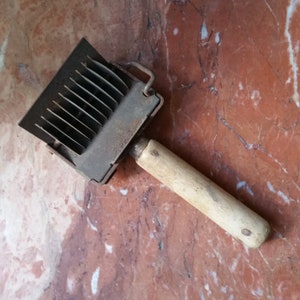 May include: A vintage metal and wood tool with a handle and a series of blades. The tool is rusty and has a worn appearance.