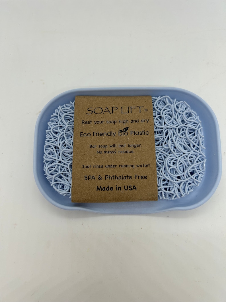 May include: A light blue soap dish made of eco-friendly bio plastic. The dish is designed to keep soap elevated and dry, preventing it from becoming soggy. The text on the label reads "SOAP LIFT, Rest your soap high and dry, Eco Friendly bio Plastic, Bar soap will last longer. No messy residue. Just rinse under running water! BPA & Phthalate Free, Made in USA."
