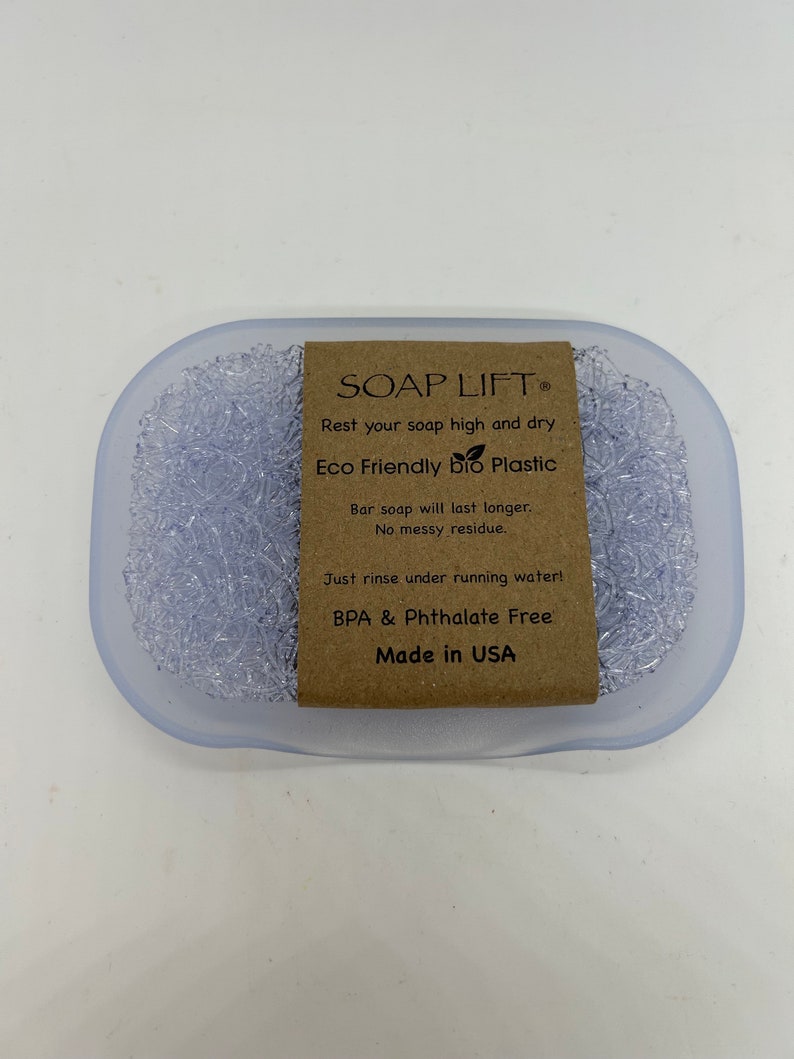 May include: A clear plastic soap dish with a textured surface. The dish has a brown label that reads "SOAP LIFT", "Rest your soap high and dry", "Eco Friendly bio Plastic", "Bar soap will last longer. No messy residue.", "Just rinse under running water!", "BPA & Phthalate Free", and "Made in USA".
