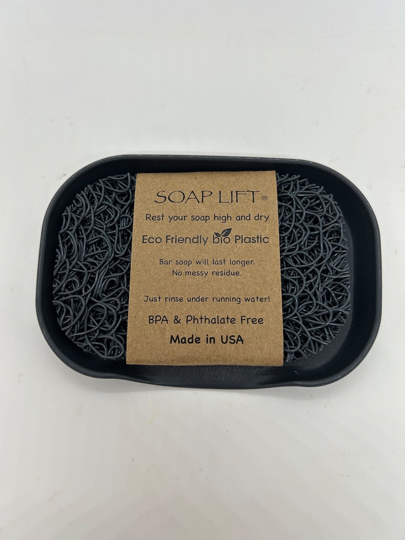 May include: A black soap dish made of eco-friendly bio plastic. The dish is designed to keep soap elevated and dry, preventing it from becoming soggy. The dish is BPA and Phthalate free and made in the USA. The text on the label reads "SOAP LIFT&reg; Rest your soap high and dry Eco Friendly bio Plastic Bar soap will last longer. No messy residue. Just rinse under running water! BPA & Phthalate Free Made in USA"