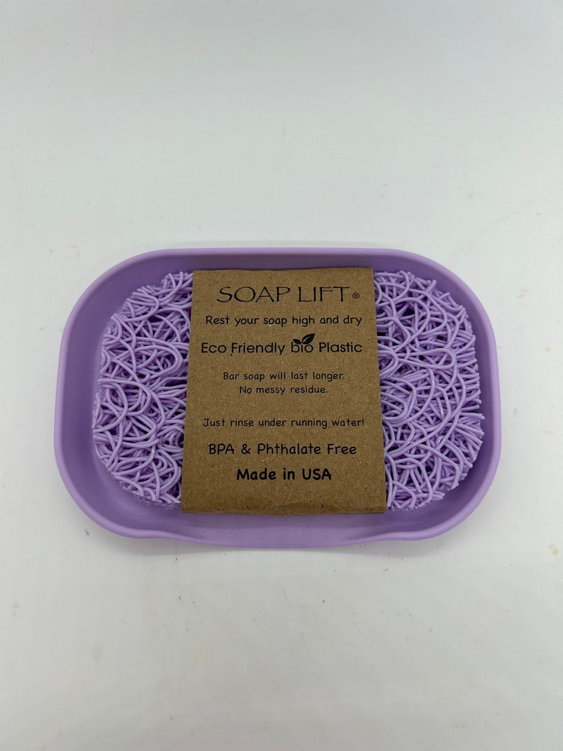 May include: Purple soap dish made of eco-friendly bio plastic. The dish features a raised, web-like design to keep soap elevated and dry. The text on the label reads "SOAP LIFT&reg; Rest your soap high and dry. Eco Friendly bio Plastic Bar soap will last longer. No messy residue. Just rinse under running water! BPA & Phthalate Free Made in USA"