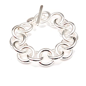 May include: A silver chain bracelet with large, interlocking circular links.