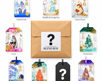 May include: A collection of eight rectangular resin amulets featuring colorful origami cranes and Japanese kanji characters, arranged around a central brown paper envelope with a white label reading ? ORIGAMI CRANE AMULET BLIND BOX.