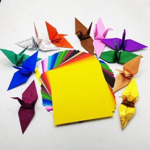 May include: A variety pack of origami paper in a rainbow of colours, with several folded origami cranes in different colours, including silver, red, blue, green, brown, pink, and gold.