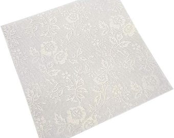 May include: A square, off-white fabric with a raised floral pattern featuring roses and leaves. The design is evenly distributed across the surface, creating a textured, decorative effect. The fabric appears to be a light, possibly delicate material.