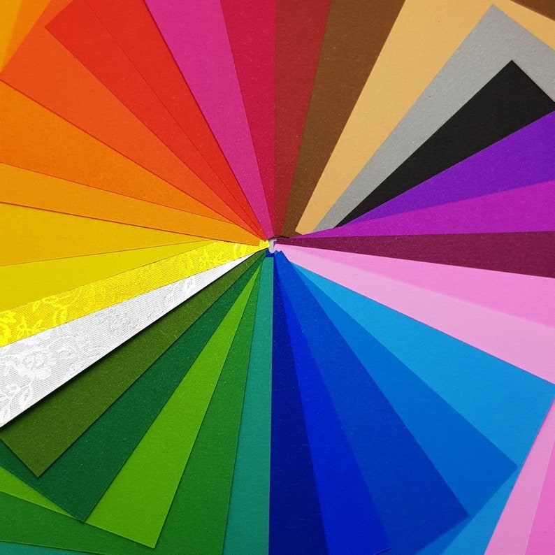 May include: A fan of colourful paper in various shades, including red, orange, yellow, green, blue, purple, pink, brown, and grey. The paper is arranged in a radial pattern, creating a vibrant and colourful display.