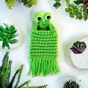May include: A green crocheted slug with googly eyes and a fringe. The slug is made with green yarn and has a crocheted body and a fringe.