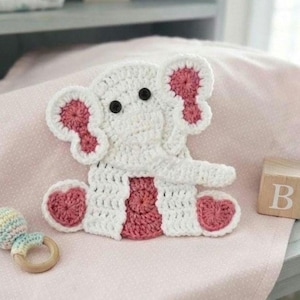 May include: A white and pink crocheted elephant applique with black button eyes. The elephant features large ears with pink centers, a trunk, and pink accents on the feet and belly. The design is flat and crafted with detailed yarn stitching.