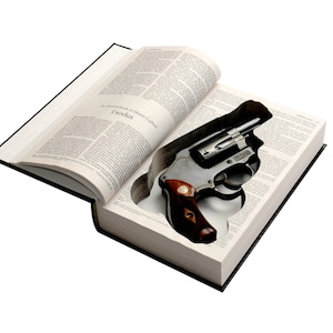 May include: A revolver nestled inside a hollowed-out book. The book is open, revealing the gun's barrel and handle. The book's pages are filled with text, and the cover is black. The gun has a silver finish with a brown handle.