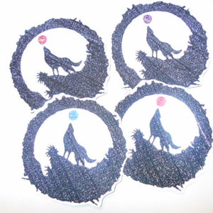 May include: Four black and white circular stickers with a wolf howling at the moon. Each sticker has a different colored moon.