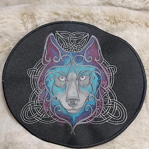 May include: A black circular patch with an embroidered image of a wolf's face in a Celtic knot design. The wolf's fur is a gradient of blue, purple, and gray.