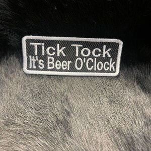 May include: Black and white embroidered patch with the text "Tick Tock It's Beer O'Clock".