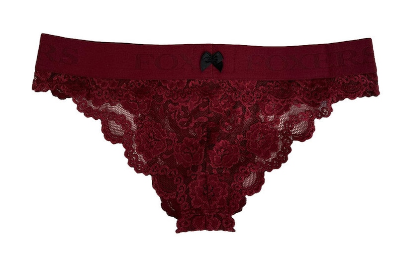 May include: Burgundy lace underwear with a black bow detail. The underwear has a wide waistband and a delicate lace pattern.