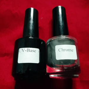 Puede incluir: Dos frascos de esmalte de uñas con tapas negras. El frasco de la izquierda es negro opaco con una etiqueta blanca que dice UV-Base. El frasco de la derecha es de vidrio transparente con una etiqueta blanca que dice Chrome. Ambos tienen tapas.
