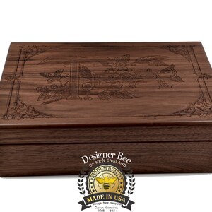 May include: A wooden box with an engraved design of a bee and flowers. The box is closed and has a label on the front that reads "Designer Bee of New England" and a logo of a bee with the words "Premium Quality Made in USA".