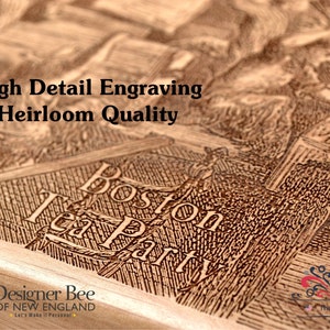 Op de afbeelding: Close-up van een houten plaquette met een gedetailleerde gravure van de Boston Tea Party. De plaquette is lichtbruin met een donkerbruine gravure. De tekst "Boston Tea Party" is zichtbaar in de gravure. De plaquette is gelabeld "High Detail Engraving Heirloom Quality" en "Designer Bee of New England".