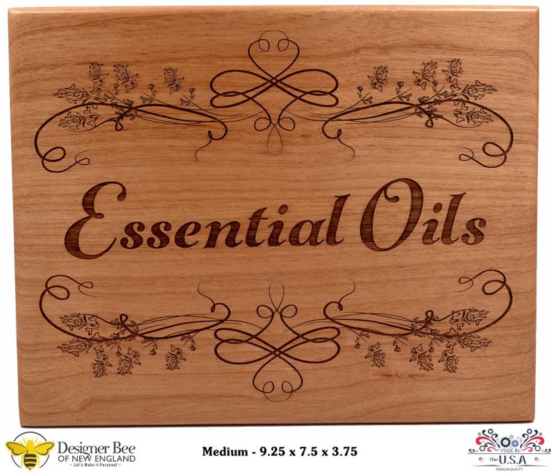 May include: A wooden sign with the words "Essential Oils" engraved in a decorative font. The sign is decorated with a floral design and has a medium size of 9.25 x 7.5 x 3.75 inches.