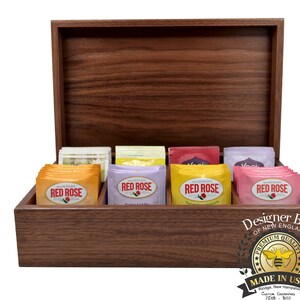 May include: A wooden box with a hinged lid, containing eight tea bags. The tea bags are labeled "Red Rose" and feature a variety of flavors. The box is made by Designer Bee of New England and has a label that says "Premium Quality" and "Made in USA".