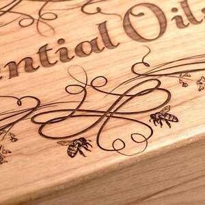 May include: A wooden box with an engraved design featuring the words "Essential Oils" and bees and flowers.