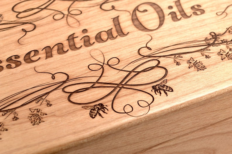 May include: A wooden box with an engraved design featuring the words "Essential Oils" and bees and flowers.