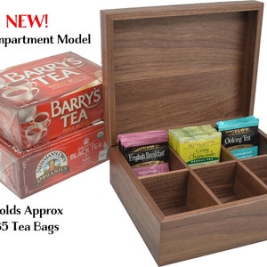 May include: A wooden tea box with six compartments, open to reveal tea bags. The box is made of dark wood and has a lid. The tea bags are in individual compartments and are labeled with different tea flavors. The box is labeled "NEW! Six Compartment Model" and "Holds Approx 85 Tea Bags".