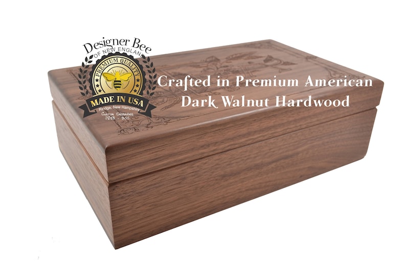 May include: A wooden box crafted from dark walnut hardwood. The box has a hinged lid and is engraved with the words "Designer Bee", "Premium Quality", "Of New England", "Made in USA", "Crafted in Premium American Dark Walnut Hardwood".