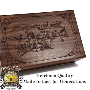 May include: A wooden box with a dark brown finish and an engraved design of leaves and the word "TEA". The box has a label that says "Designer Bee of New England" and "Premium Quality Made in USA".
