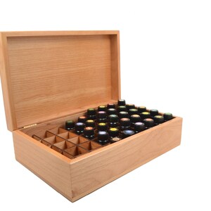 May include: A wooden box with a hinged lid, open to reveal a grid of compartments filled with small bottles. The bottles have black caps with colorful tops.