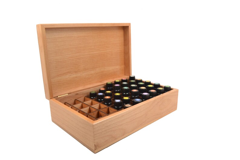 May include: A wooden box with a hinged lid, open to reveal a grid of compartments filled with small bottles. The bottles have black caps with colorful tops.