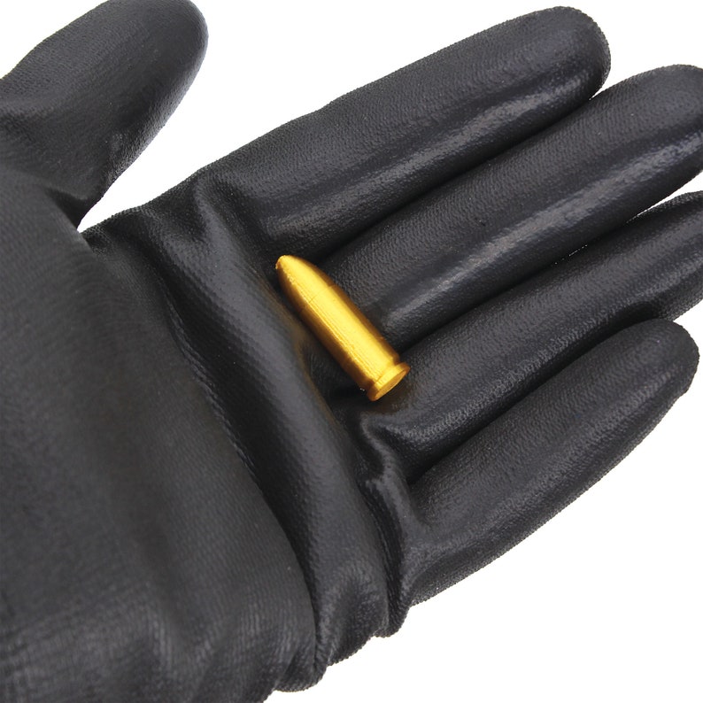 May include: A gold-colored bullet is held in a black work glove.