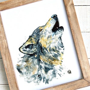 May include: Watercolor painting of a howling wolf in a wooden frame. The artwork features shades of gray, yellow, and blue, with the wolf's head and open mouth prominently displayed. The frame is made of light brown wood.