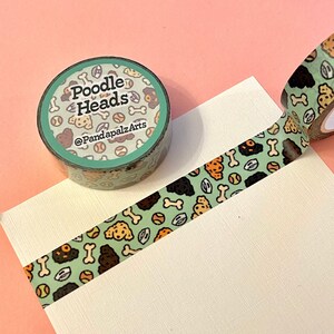 May include: A roll of washi tape with a green background and a repeating pattern of brown poodle heads, bones, and tennis balls. The tape is labelled "Poodle Heads" and "@PandapalzArts".