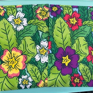 Op de afbeelding: Een naadloos patroon met kleurrijke bloemen met gele centra en groene bladeren. De bloemen zijn in tinten rood, paars, wit en geel.