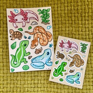Op de afbeelding: Twee rechthoekige stickervellen met illustraties van een roze axolotl, een bruine schildpad, een beige slang, een groene hagedis met witte strepen, een blauwe kikker, een kleine bruine muis, groene waterplanten en kleine blauwe bubbels.