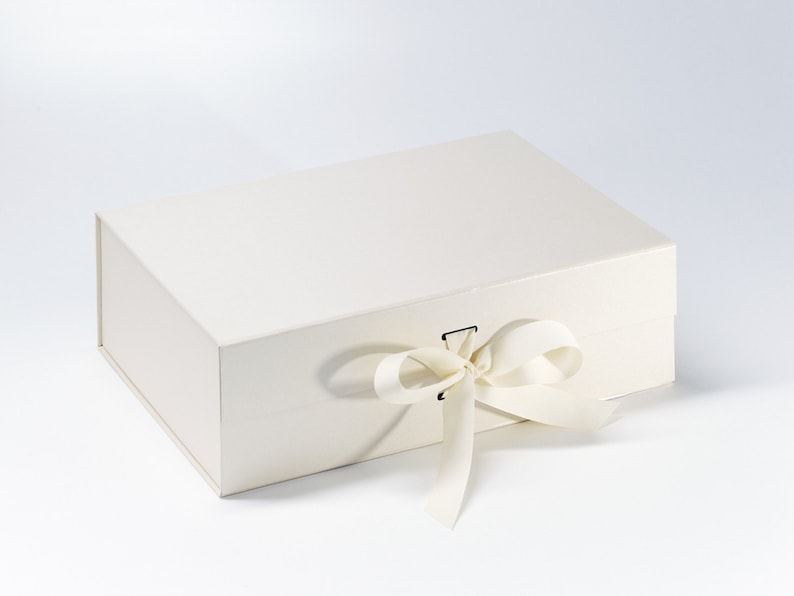 May include: A white gift box with a white satin ribbon tied in a bow. The box is closed and has a small metal clasp.