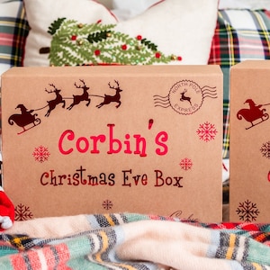 Personalized kraft Christmas eve box with red chrome holiday theme design. Design made to look like it's straight from the north pole. Gift box is displayed in a cozy holiday setting.