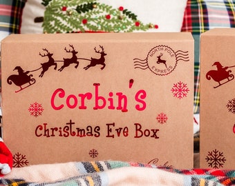 May include: A brown cardboard box with a red and white Christmas Eve box design. The box is decorated with reindeer, snowflakes, and a North Pole Express stamp. The text on the box reads "Corbin's Christmas Eve Box".