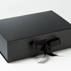 May include: A black gift box with a black satin ribbon tied in a bow.