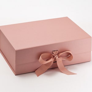May include: A blush pink gift box with a satin ribbon tied in a bow.