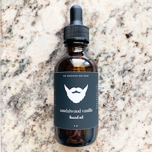 May include: A 2 ounce bottle of sandalwood vanilla beard oil. The bottle is amber glass with a black dropper and a black label with a white beard icon and the text "sandalwood vanilla beard oil".