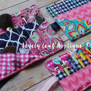 May include: Three fabric rolls with different patterns and colors. The rolls are filled with various items, including makeup brushes, crayons, and knitting needles. The rolls are made of pink, blue, and green fabrics with white stitching. The text "Lovely Leaf Applique" is visible on the image.