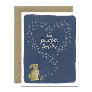 May include: A sympathy card with a blue background and a white heart shape made of dandelion seeds. The text "With Heartfelt Sympathy" is written in yellow inside the heart. A small brown rabbit is looking up at the heart.