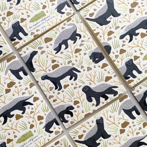 May include: A set of 10 notecards featuring a repeating pattern of honey badgers and bees on a white background. The notecards are printed with the text "Yeppe Paper Los Angeles, California www.yeppepaper.com made in USA".