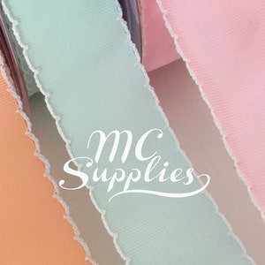 May include: Close-up of three spools of ribbon in pastel colours: peach, mint green, and pink. Each ribbon has a textured surface and a white, frayed edge. The text "MC Supplies" is visible in the image.