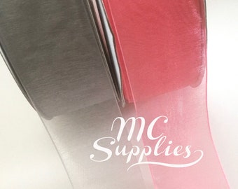 May include: Two rolls of sheer ribbon, one gray and one pink. The ribbon is rolled and the ends are visible. The ribbon is translucent and has a slight sheen.