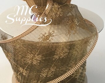 May include: A spool of gold mesh ribbon with a snowflake pattern. The ribbon has a gold glitter finish and a wired edge.