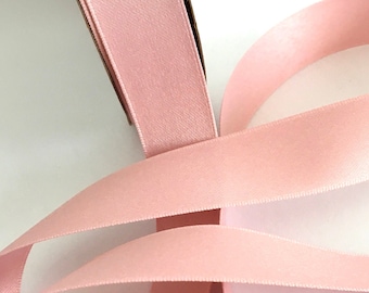 Könnte beinhalten: Eine Rolle blasses rosa Satinband. Das Band ist weich und glatt mit einem dezenten Glanz.